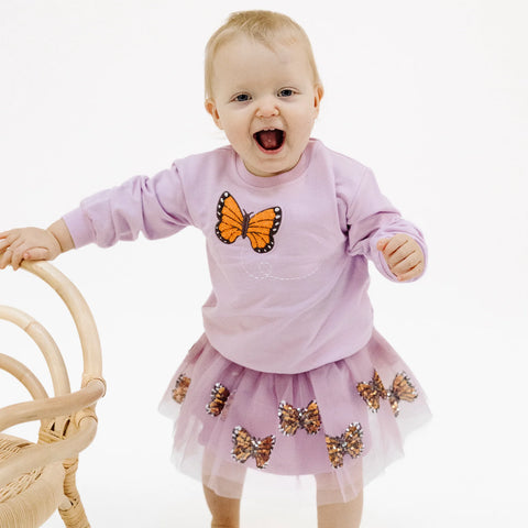 Image shows a baby wearing the tutu skirt and a matching sweatshirt
