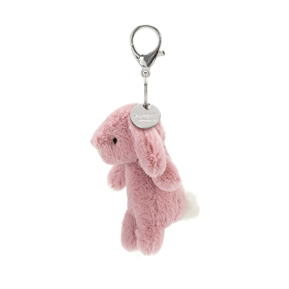 The side view of a light pink stuffed bunny hanging from a clip keychain