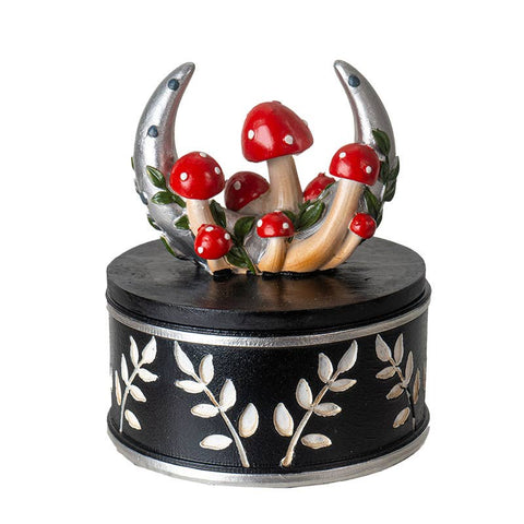 Image shows a round, black and white box. The lid has a crescent moon and redcap mushrooms.