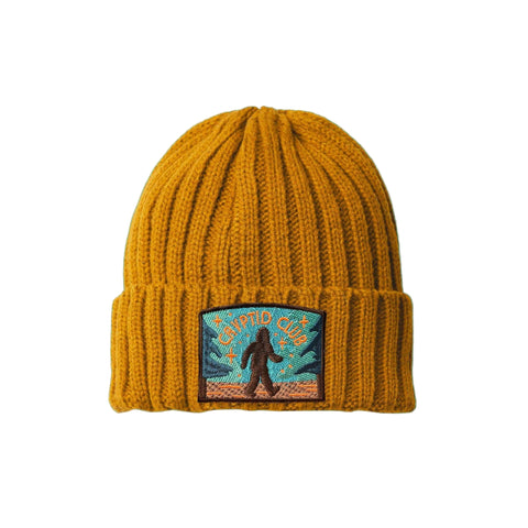 Yellow beanie with a bigfoot "Cryptid Club" patch on a white background