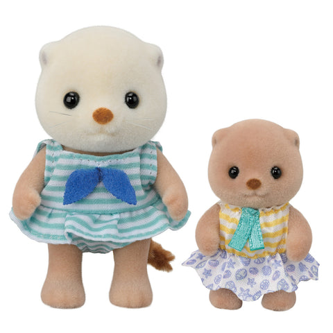 Two sea otter toys, one in a blue dress with white stripes and another in a floral dress, on a white background.