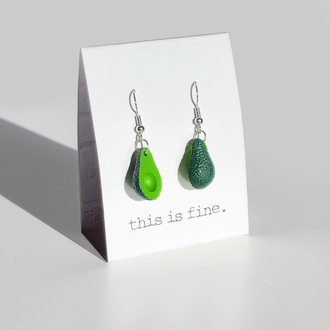Image shows a pair of avocado earrings hanging from silver wires