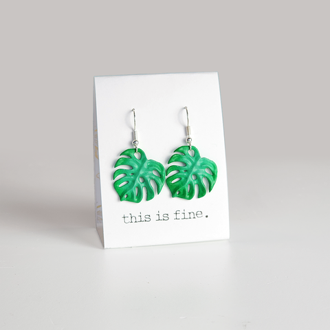 Image shows a pair of monstera leaf earrings hanging from silver wires
