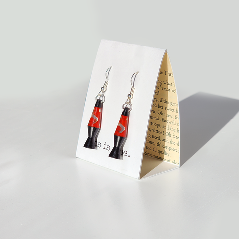 Image shows a pair of red and black lava lamp earrings hanging from silver wires