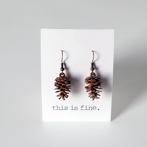Image shows a pair of pinecone shaped earrings hanging from silver wires