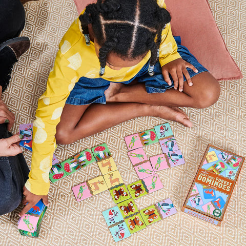 Image shows a child playing with the dominoes