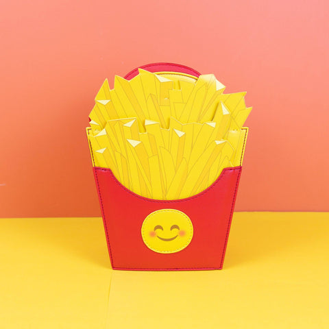 Image shows a crossbody bag in the shape of french fries in a red container. The container has a smiley face.