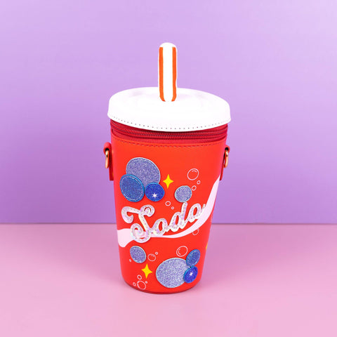 Image shows a crossbody bag in the shape of a red soda cup. It has blue bubbles and says "soda"
