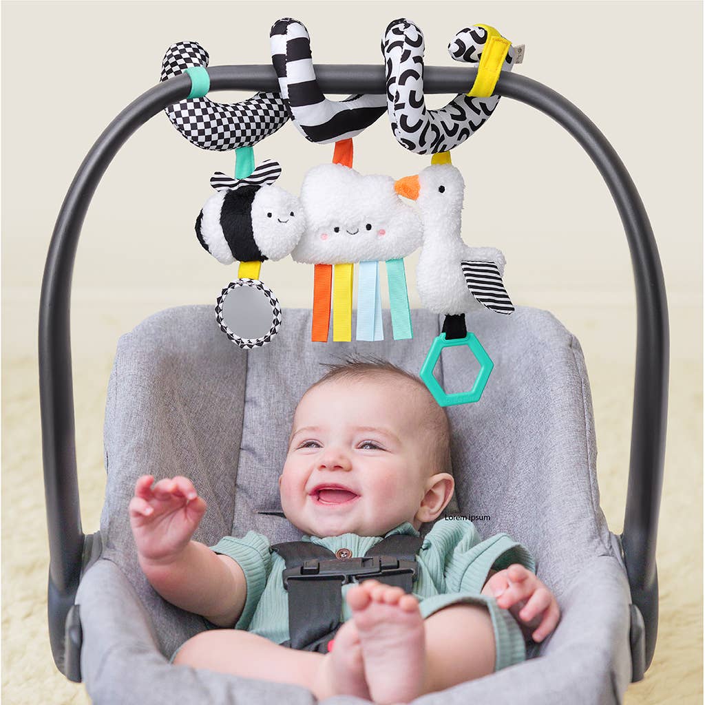 Image shows the toy hanging from a car seat with a baby happily playing with it