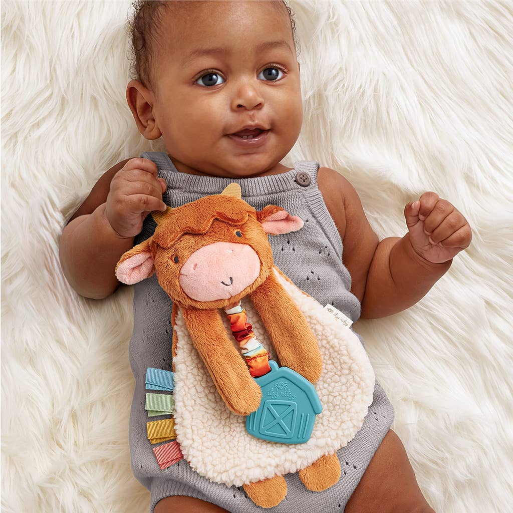 Image shows an African American baby holding the Highland Cow lovey