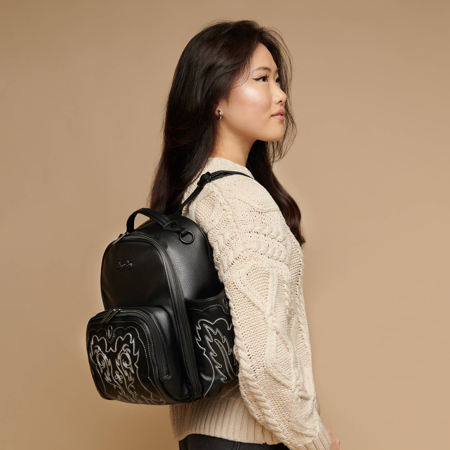 Image shows a woman with long black hair wearing the backpack style diaper bag