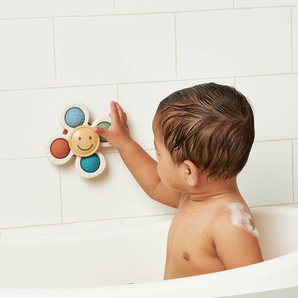 Image depicts a baby playing with the product suction cupped to the side of the bathtub