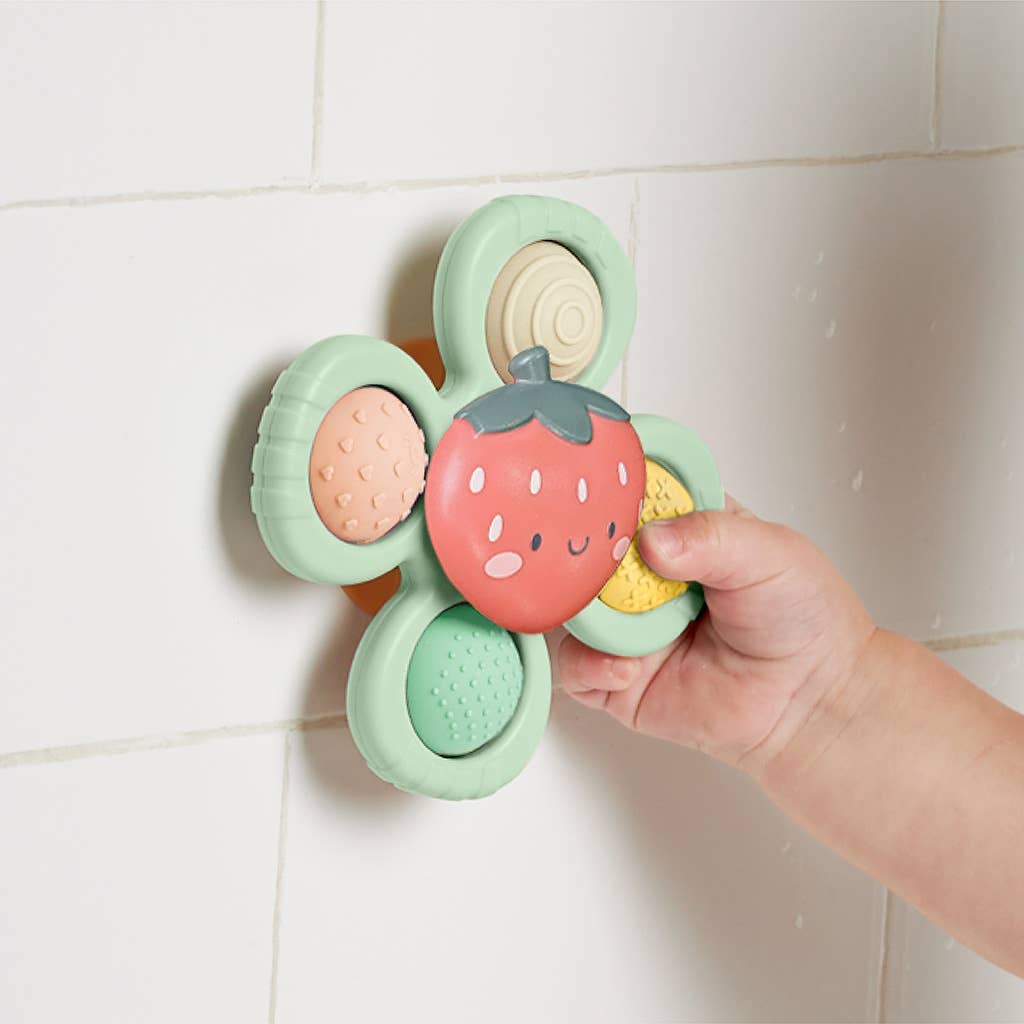 Image depicts the toy stuck to the side of the bathtub with a baby's hand pulling at it