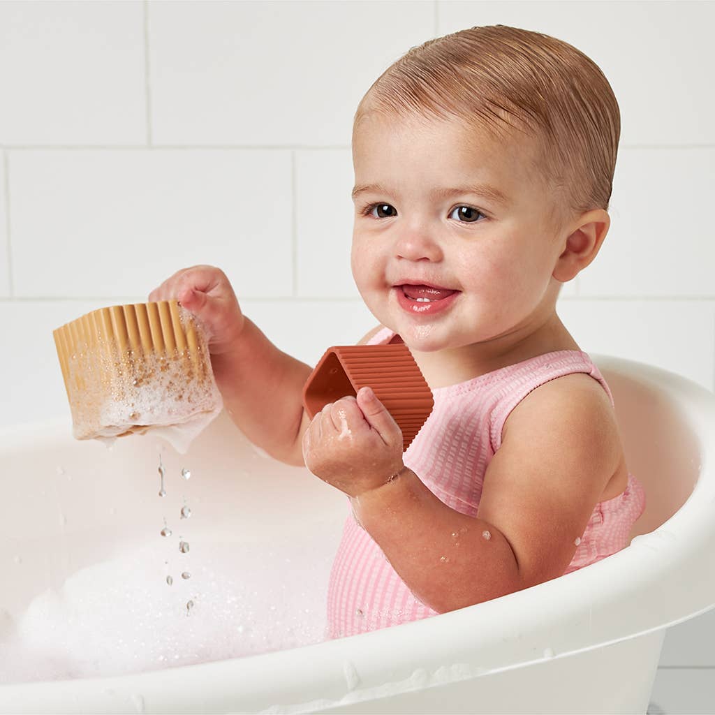 Image shows a baby playing with the blocks in the bath