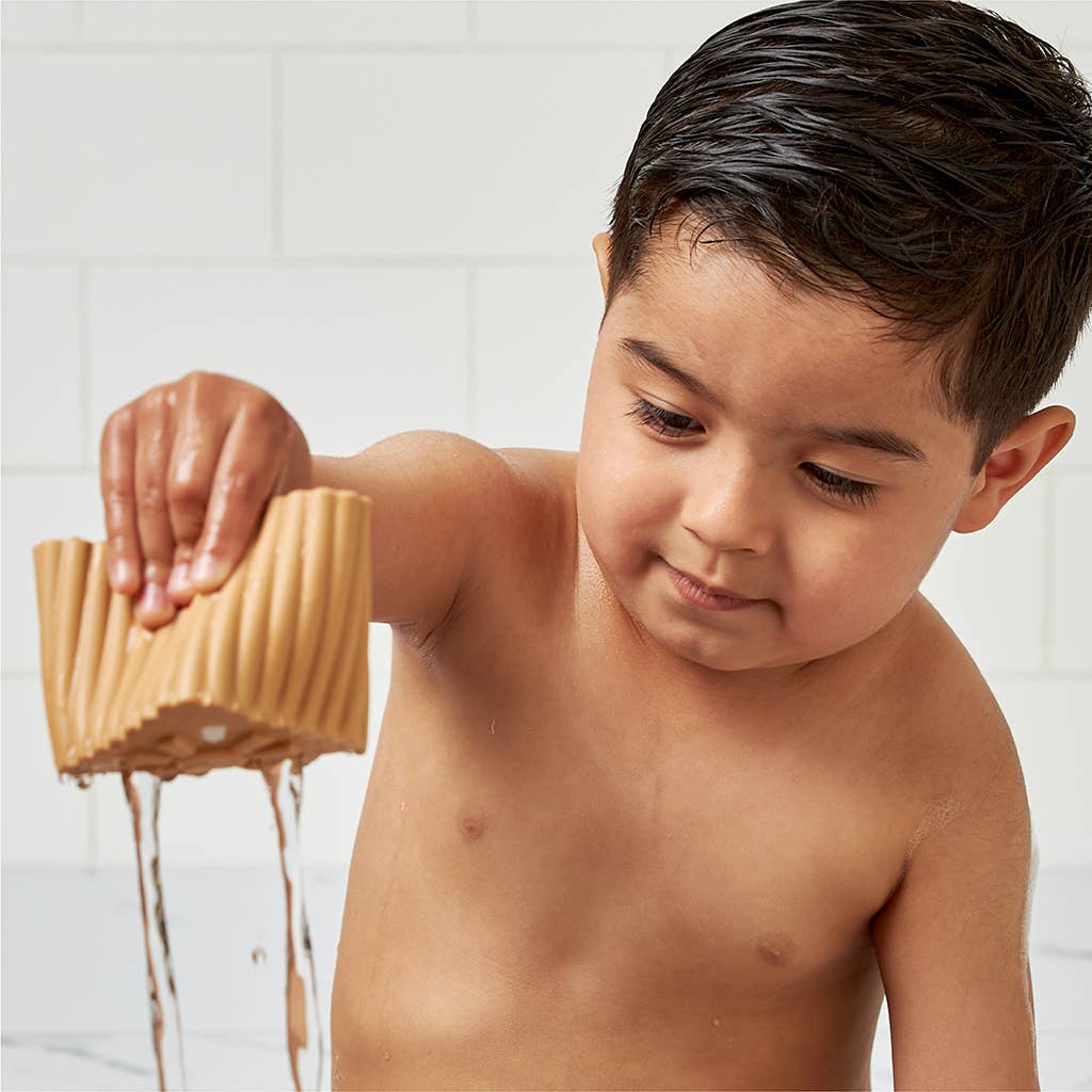 Image shows a young toddler playing with one of the blocks in the bath