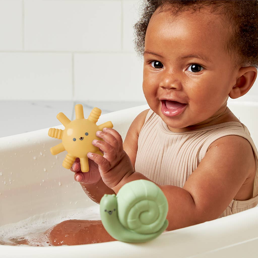 Image shows an African American baby in the bath playing with two of the bath toys - the sun and the snail