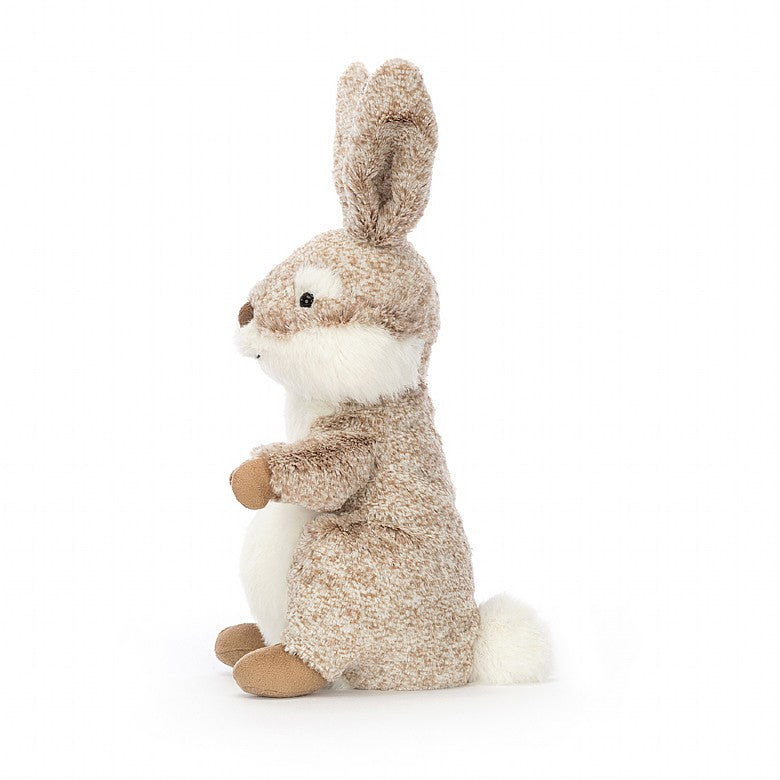 The side view of A seated stuffed rabbit with patterned tan fur and tall ears