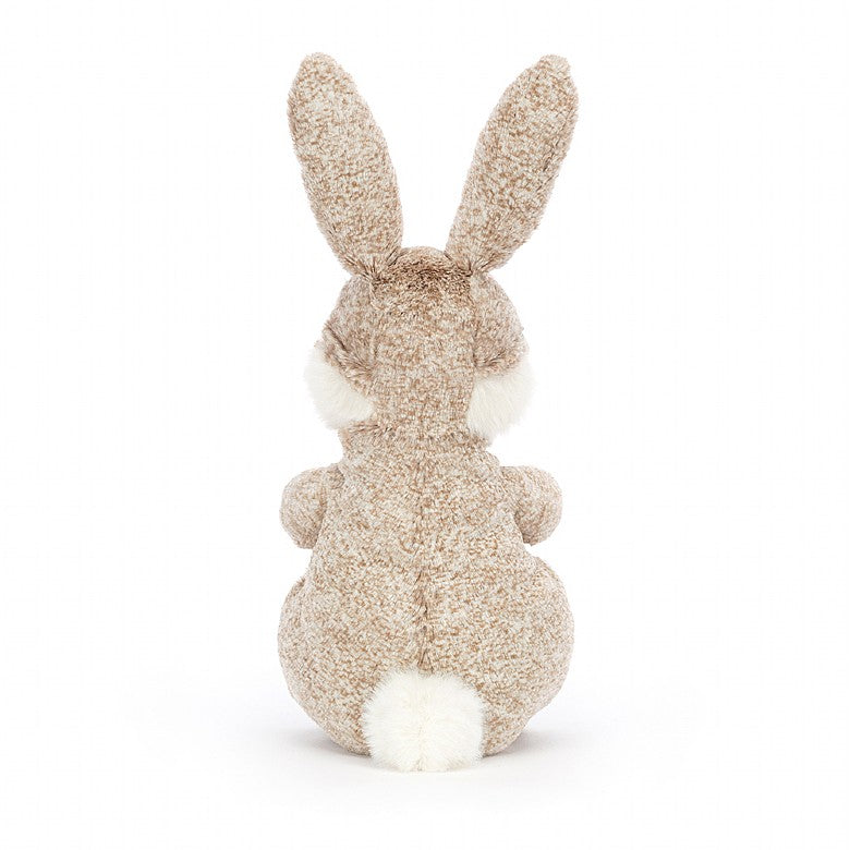 The back view of A seated stuffed rabbit with patterned tan fur and tall ears