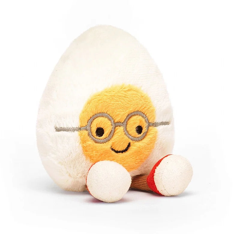 A seated, stuffed boiled egg wearing wire rimmed glasses and red sneakers