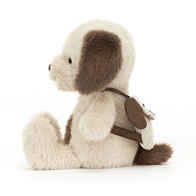 A stuffed brown and white puppy wearing a backpack