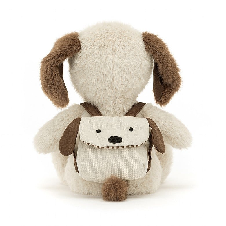 A stuffed brown and white puppy wearing a backpack. The backpack has a puppy face.