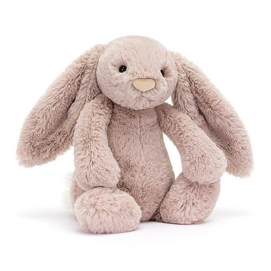 A stuffed, rose-colored bunny with floppy ears and a pink nose