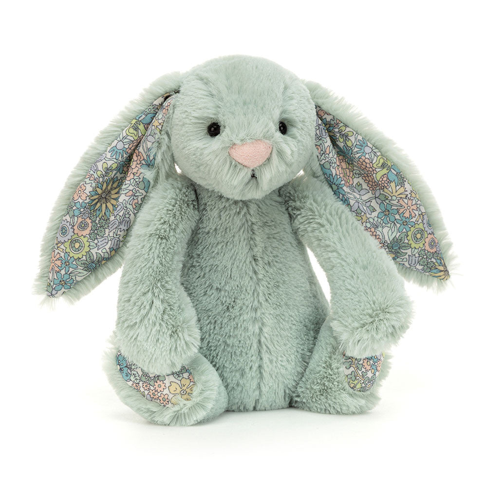 A minty green stuffed bunny with floral fabric on the bottom of its feet and inside its floppy ears