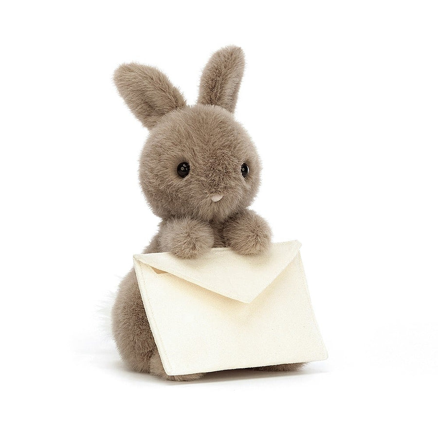 A mocha-colored stuffed bunny holding a cream-colored envelope