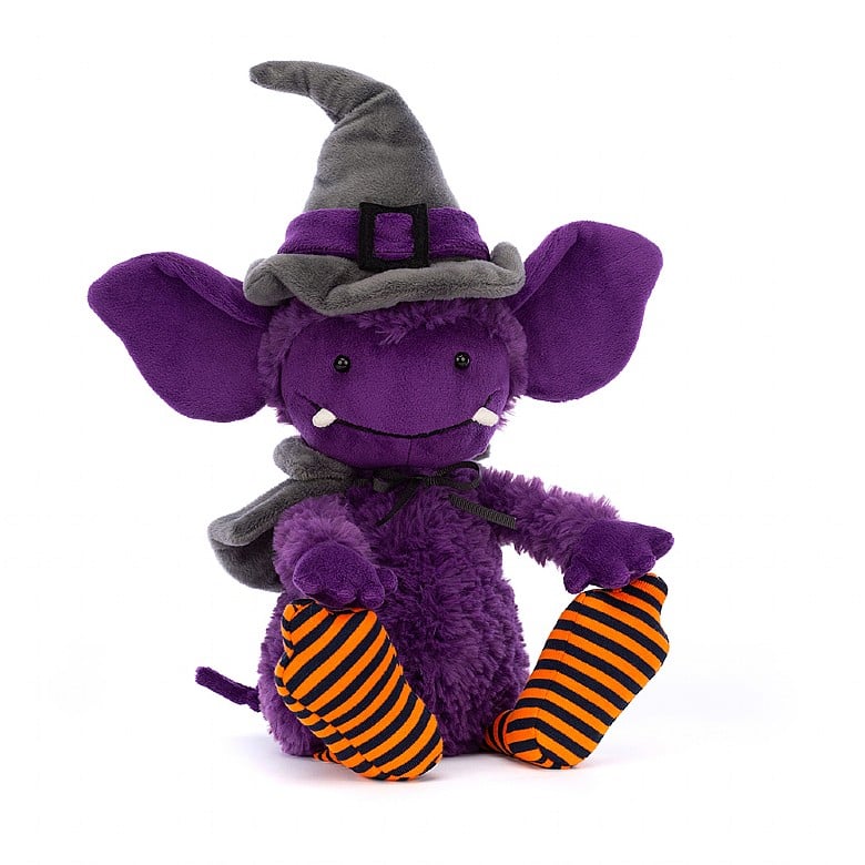 A purple gremlin with fangs and large ears. She wears a grey witch hat, a cape, and orange and black striped stockings.