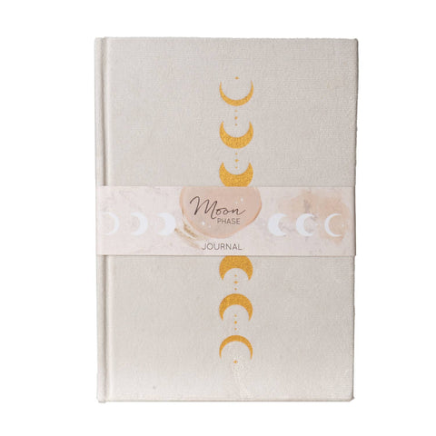 Image shows the front of a journal. The cover is velvet, white, with gold moon phases.