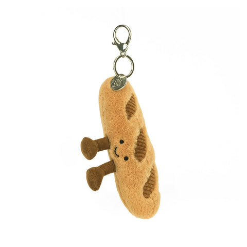 Image shows a stuffed baguette hanging from a silver clip keychain. It has a happy face and feet.