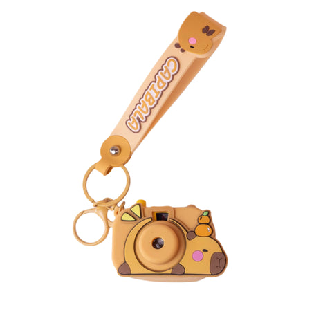 Image shows a sleeping capybara attached to a strap keychain. The capybara has a projector in its belly.