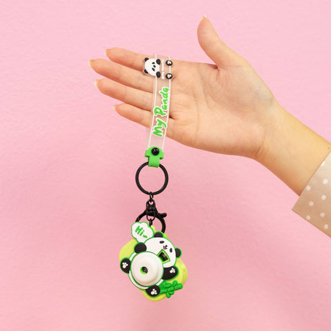 Image shows a mini panda projector camera hanging from a keychain clear strap. The panda is on a green background.