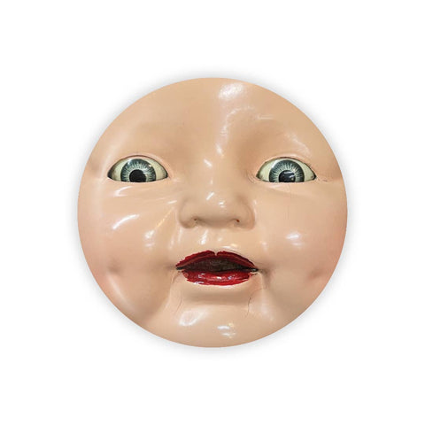 Image shows a magnet in the form of a plastic doll. It has grey eyes and parted red lips.