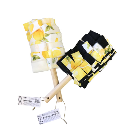 Two fleece fabric dusters with a wooden handle. Both fabrics have lemons on a white background. One alternates with white fabric and the other with black.