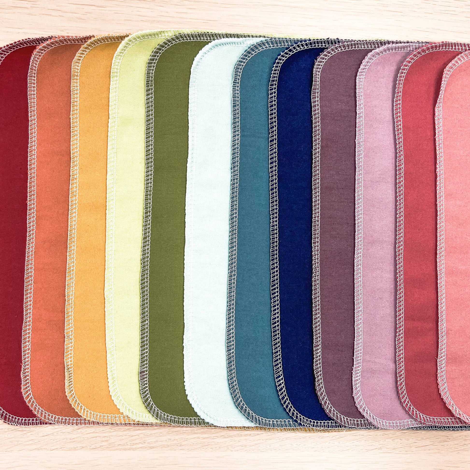 The fabric towels laid out flat in rainbow order