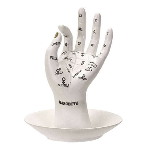 Image shows a ring holder in the shape of a hand. It has various palmistry symbols over the entire hand.