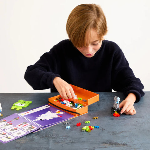 Child playing with building blocks and a manual on a table