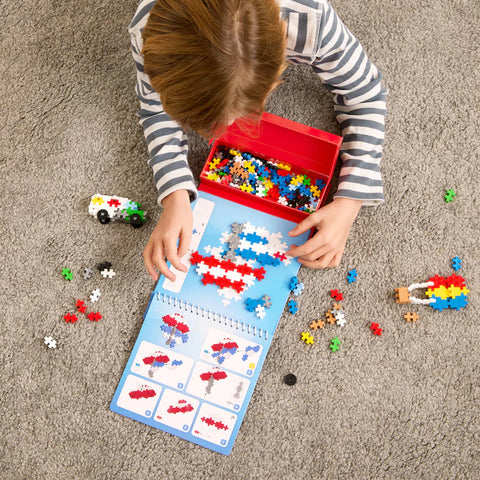 Child playing with building blocks and a color chart on a carpeted floor