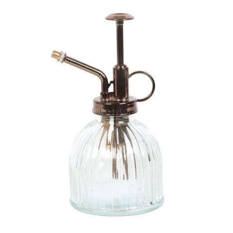 Image shows a ribbed glass plant mister with bronze colored metal for the top.