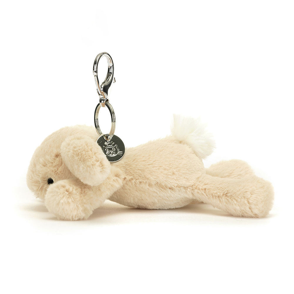 The side view of A floppy stuffed oatmeal colored bunny hanging from a clip keychain