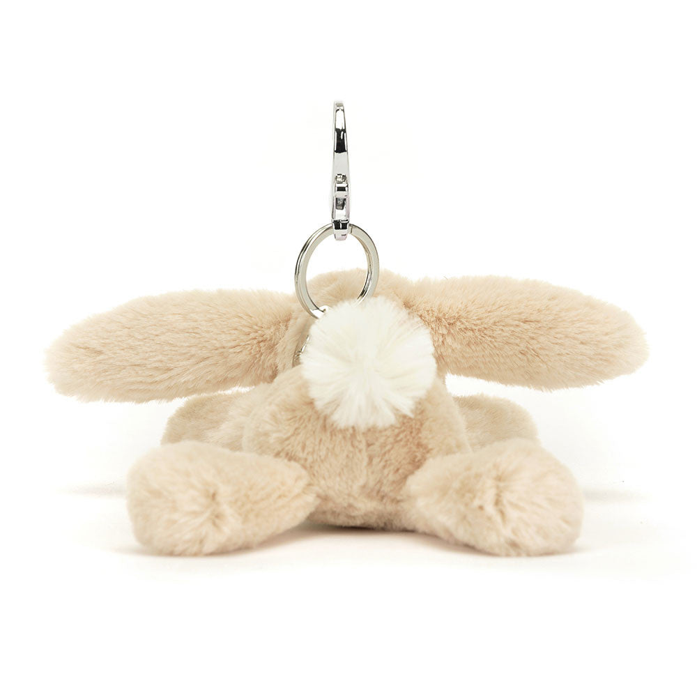 The back view of A floppy stuffed oatmeal colored bunny hanging from a clip keychain