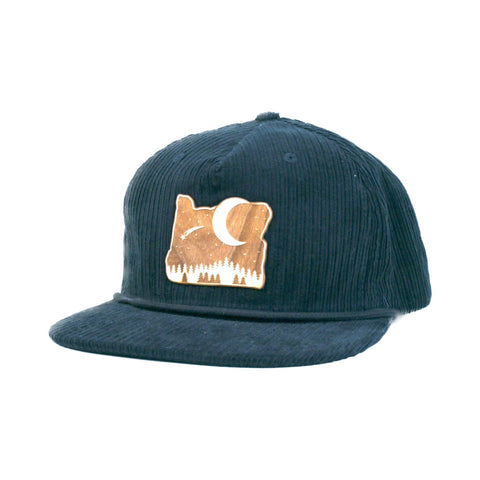 Image shows a navy-colored corduroy snapback hat. It has a wood patch with a night scene.