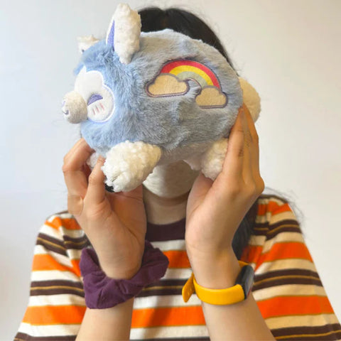 A woman holds the cloudy-themed stuffed kitsune. It is slightly smaller than her head.