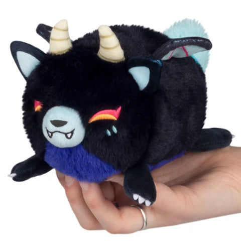 A stuffed demon-themed Kitsune. It is black with wings and horns, a purple belly, and orange eyes.