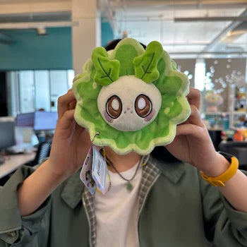 A woman holds the plush turnip moth in front of her face. It is slightly smaller than her head.