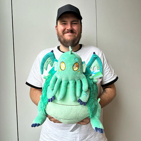 Image shows a man holding the stuffed baby Cthulu. It is about the size of his torso.