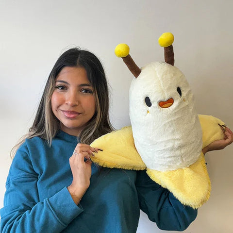 A woman holds the plush banana slug. It is about the size of her torso.