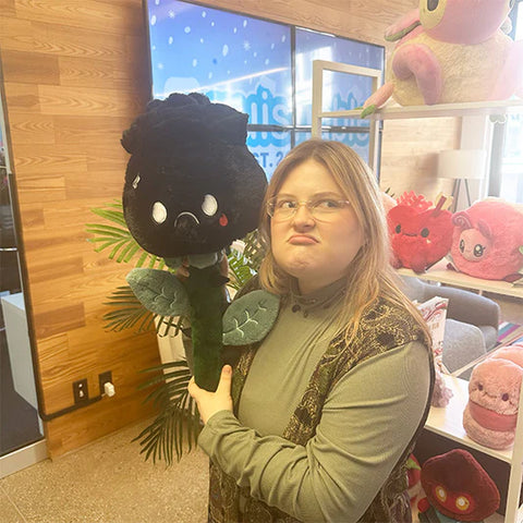 Image shows a woman holding the stuffed black rose. The petals are slightly larger than her head.