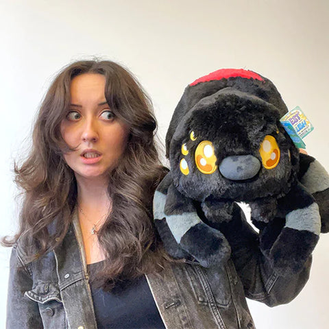Image shows a woman holding the stuffed Black Widow up to her face. It is larger than her head.